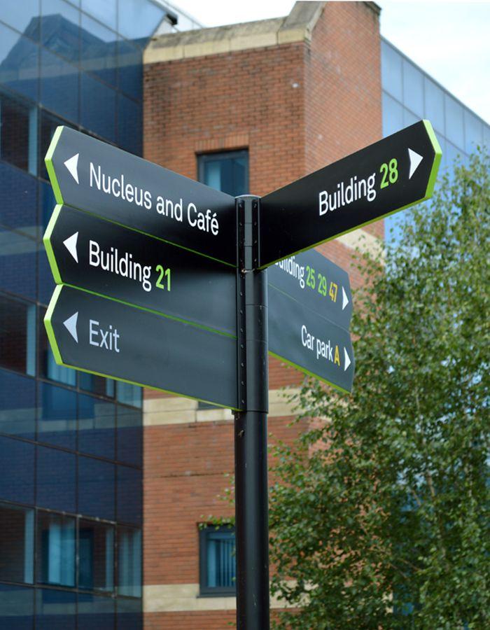 Poteau de signalétique avec flèches directionnelles devant un bâtiment